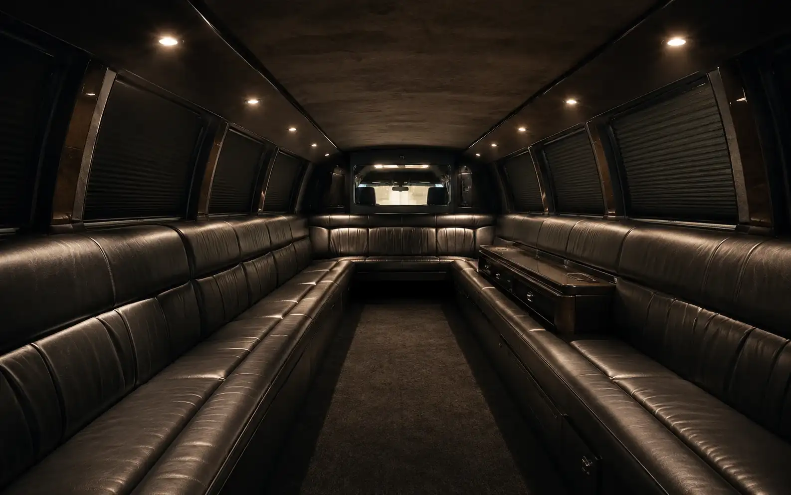 The cabin of a stretch limousine: leather benches along both side walls facing inward, with a divider at the far end.
