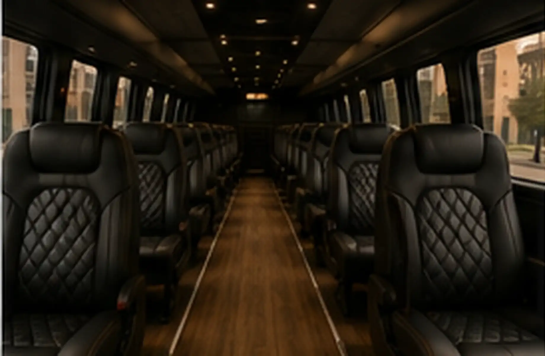 The cabin of an executive party coach: quilted black leather seats down both sides of a centre aisle.